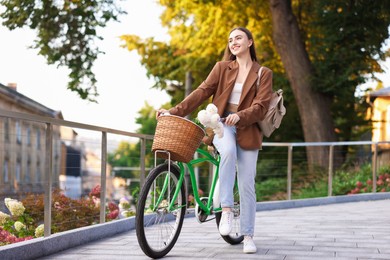 Photo of Woman walking her bicycle with flowers in basket outdoors