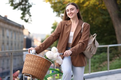 Photo of Woman walking her bicycle with flowers in basket outdoors