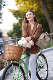 Photo of Woman riding bicycle with flowers in basket on city street