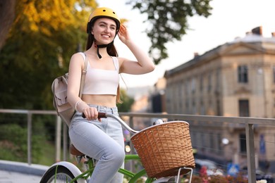 Photo of Woman in helmet riding bicycle on city street. Space for text