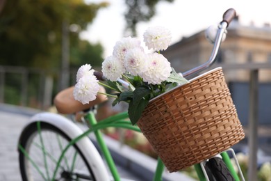 Photo of Bicycle with beautiful flowers in basket on city street, closeup