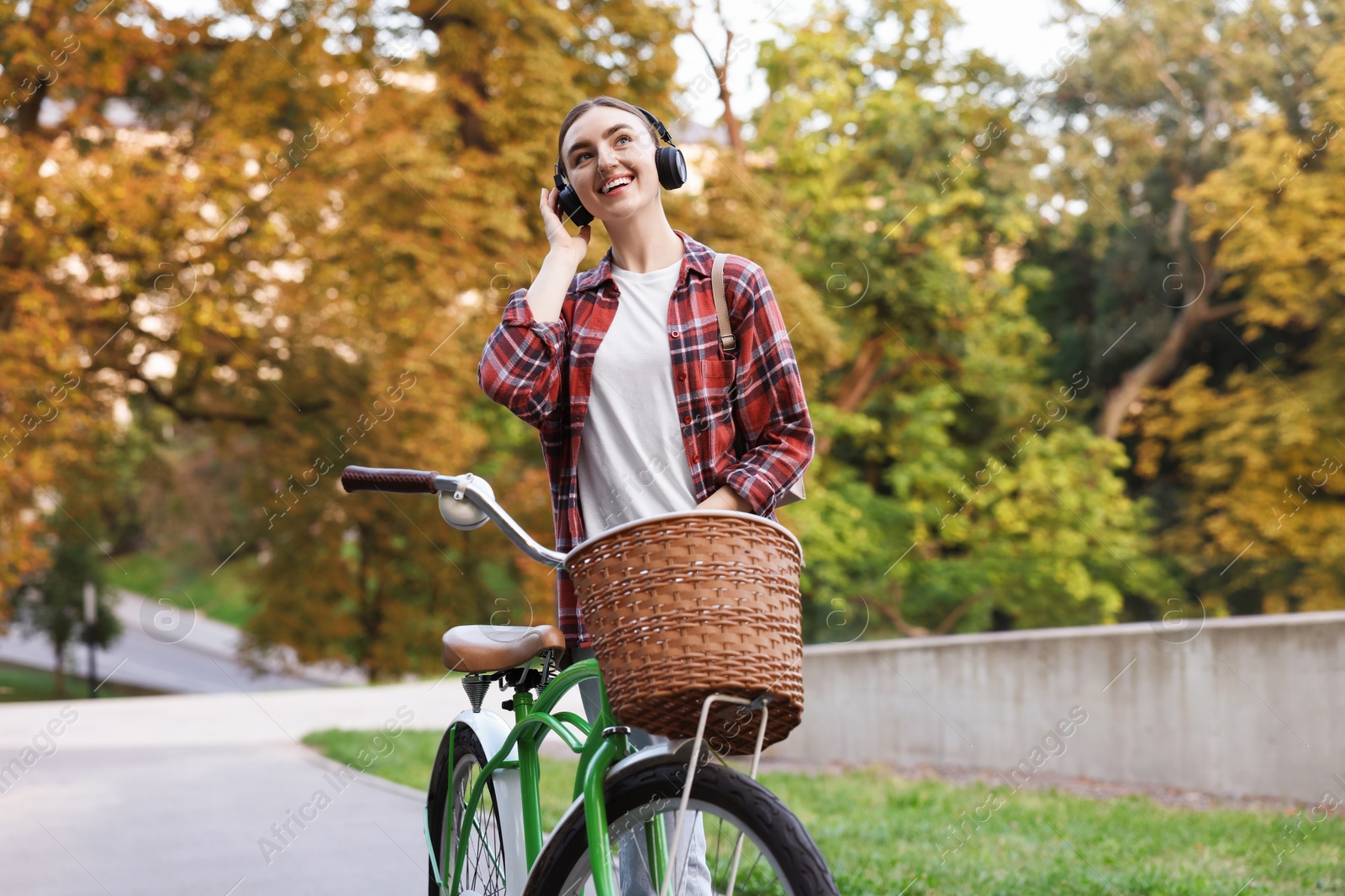 Photo of Beautiful woman listening to music while riding bicycle in park