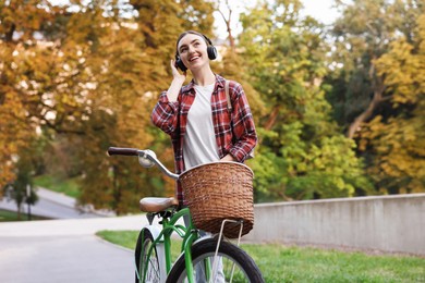 Photo of Beautiful woman listening to music while riding bicycle in park