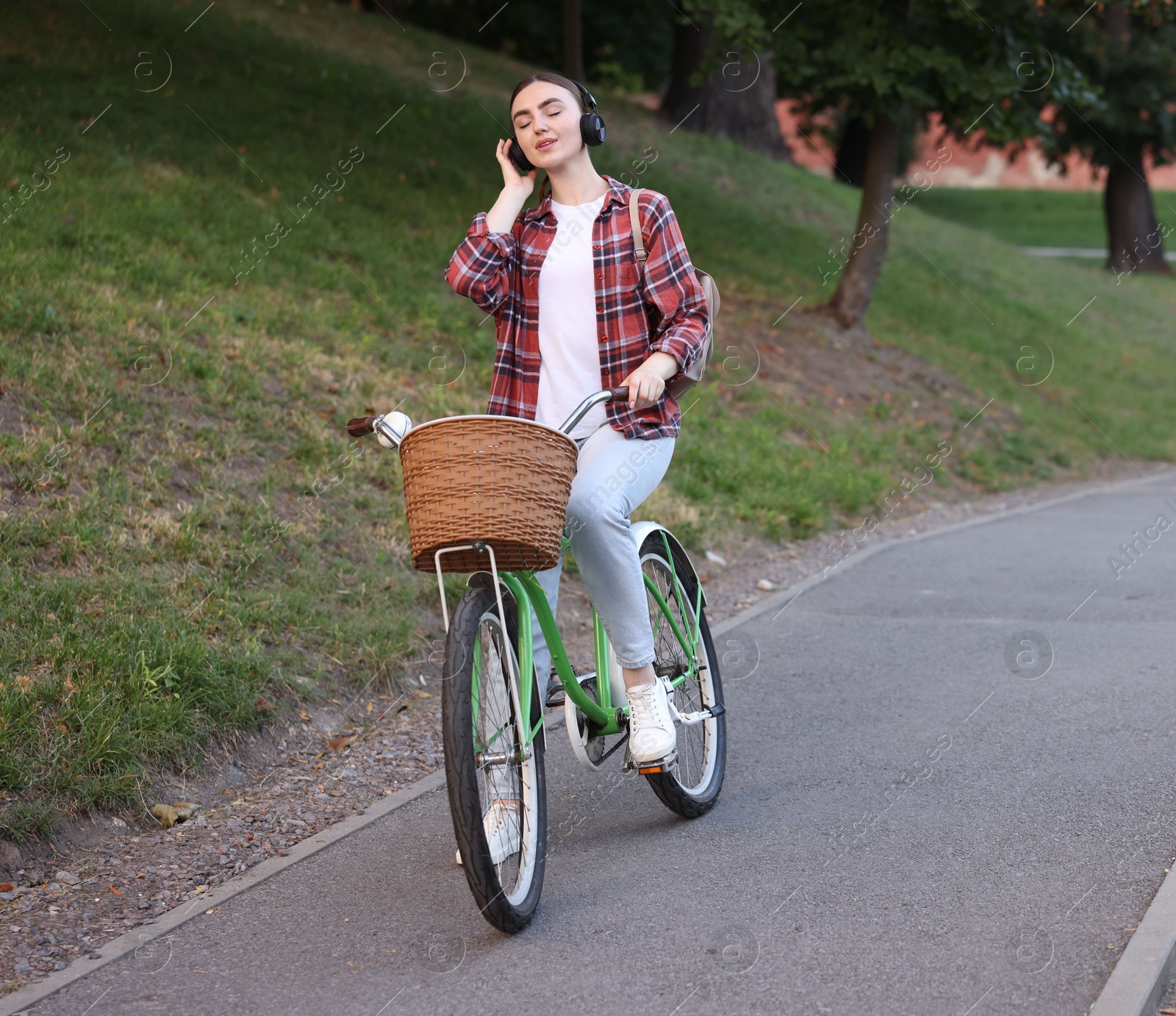 Photo of Beautiful woman listening to music while riding bicycle in park