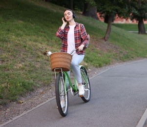 Photo of Beautiful woman listening to music while riding bicycle in park