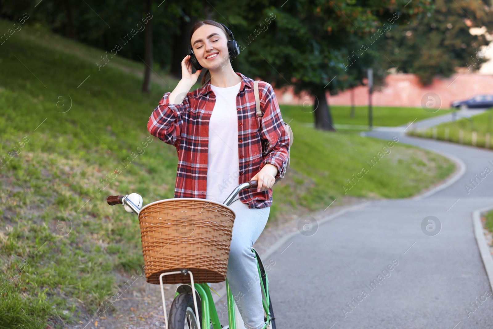 Photo of Beautiful woman listening to music while riding bicycle in park