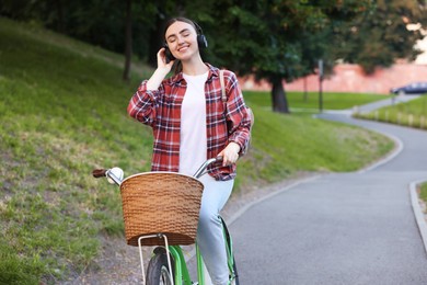 Photo of Beautiful woman listening to music while riding bicycle in park