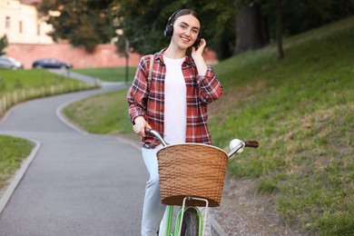 Photo of Beautiful woman listening to music while riding bicycle in park