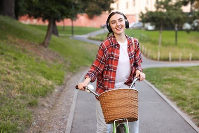Photo of Beautiful woman listening to music while riding bicycle in park. Space for text