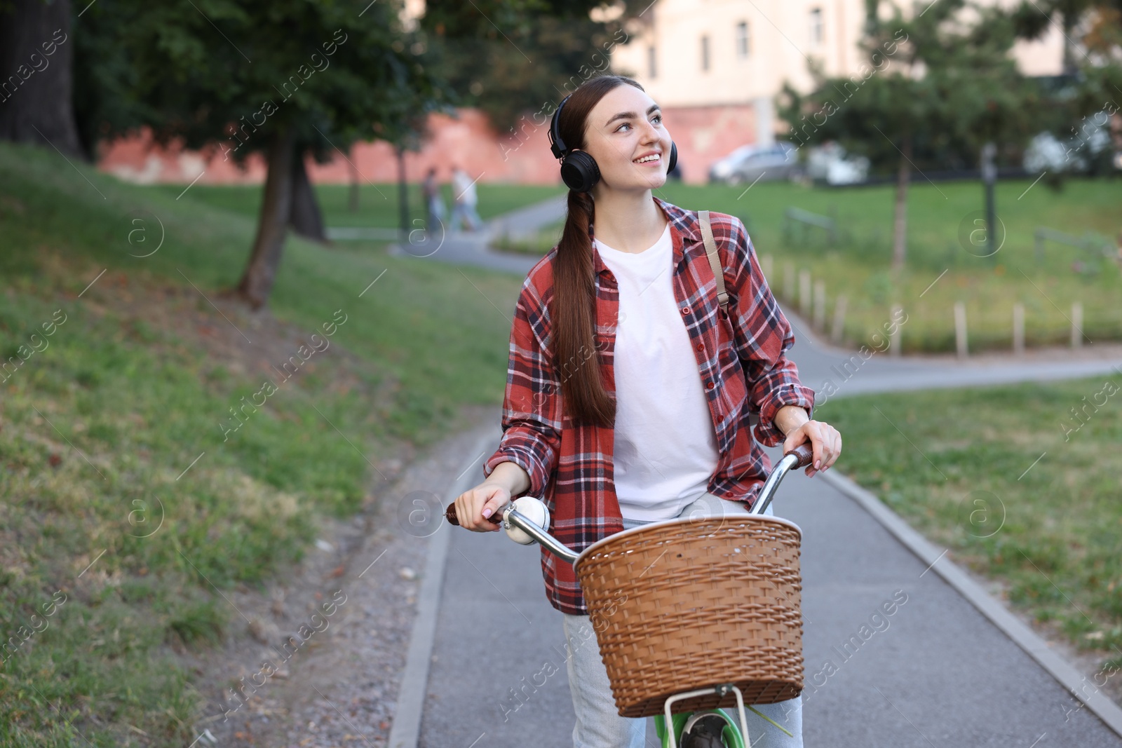 Photo of Beautiful woman listening to music while riding bicycle in park