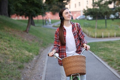 Photo of Beautiful woman listening to music while riding bicycle in park