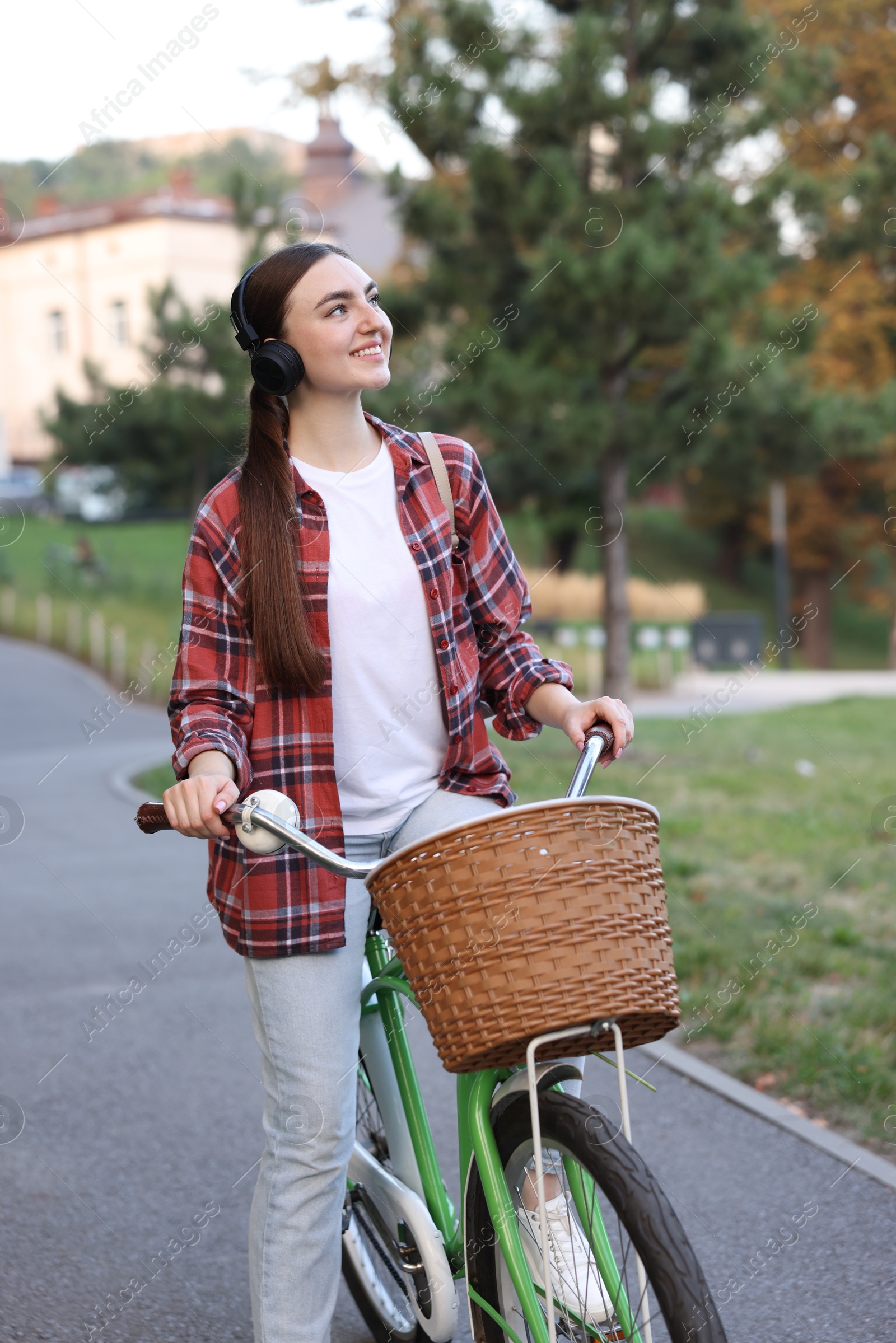 Photo of Beautiful woman listening to music while riding bicycle in park