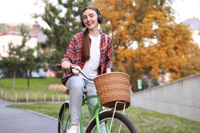 Photo of Beautiful woman listening to music while riding bicycle in park