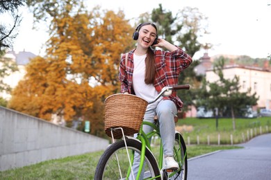 Photo of Beautiful woman listening to music while riding bicycle in park
