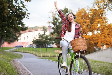 Photo of Beautiful woman listening to music while riding bicycle in park. Space for text
