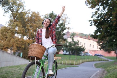 Photo of Beautiful woman listening to music while riding bicycle in park. Space for text