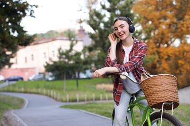 Photo of Beautiful woman listening to music while riding bicycle in park. Space for text