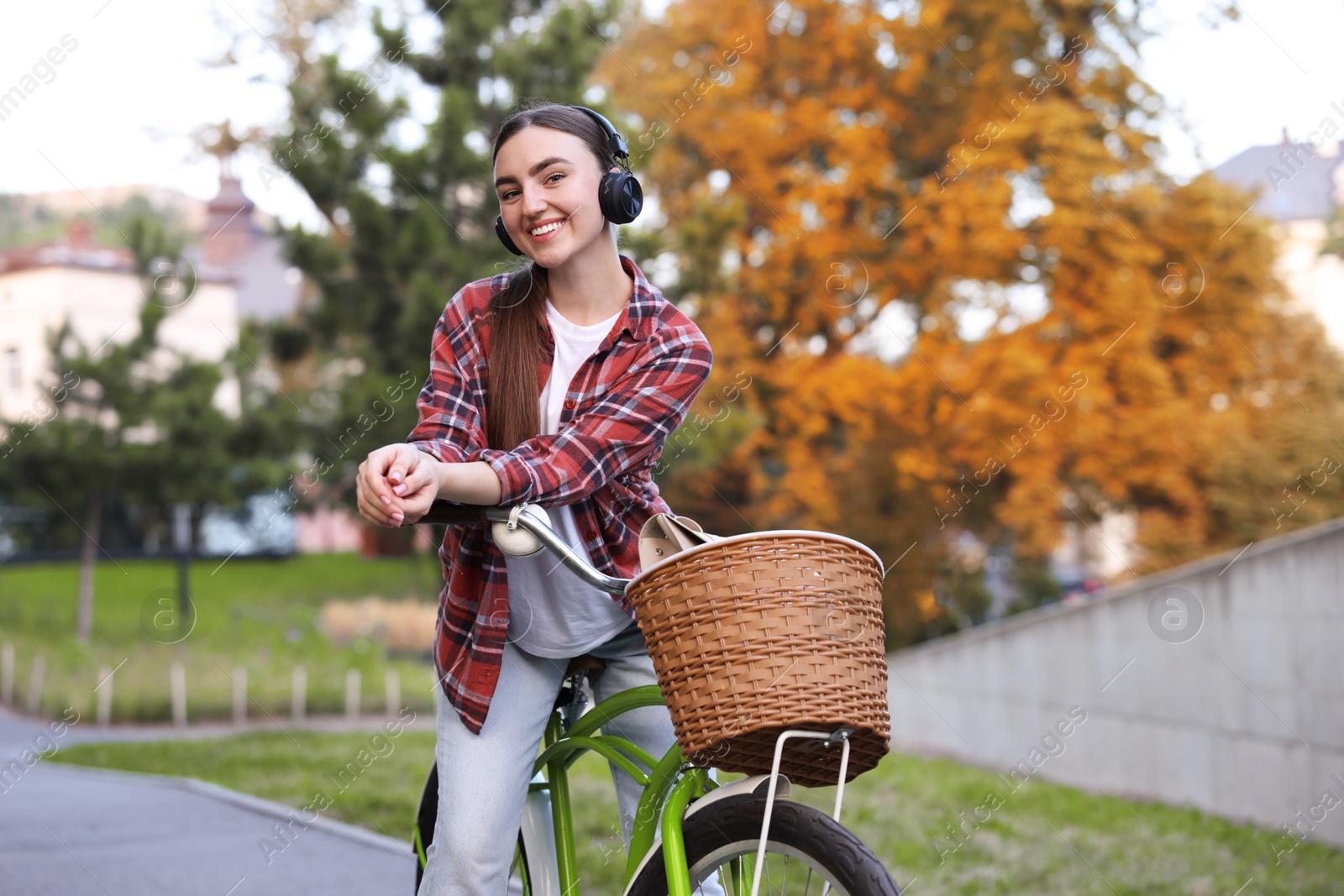 Photo of Beautiful woman listening to music while riding bicycle in park. Space for text