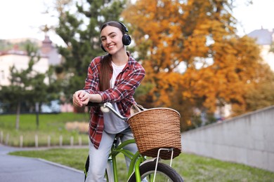 Photo of Beautiful woman listening to music while riding bicycle in park. Space for text