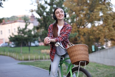 Photo of Beautiful woman listening to music while riding bicycle in park