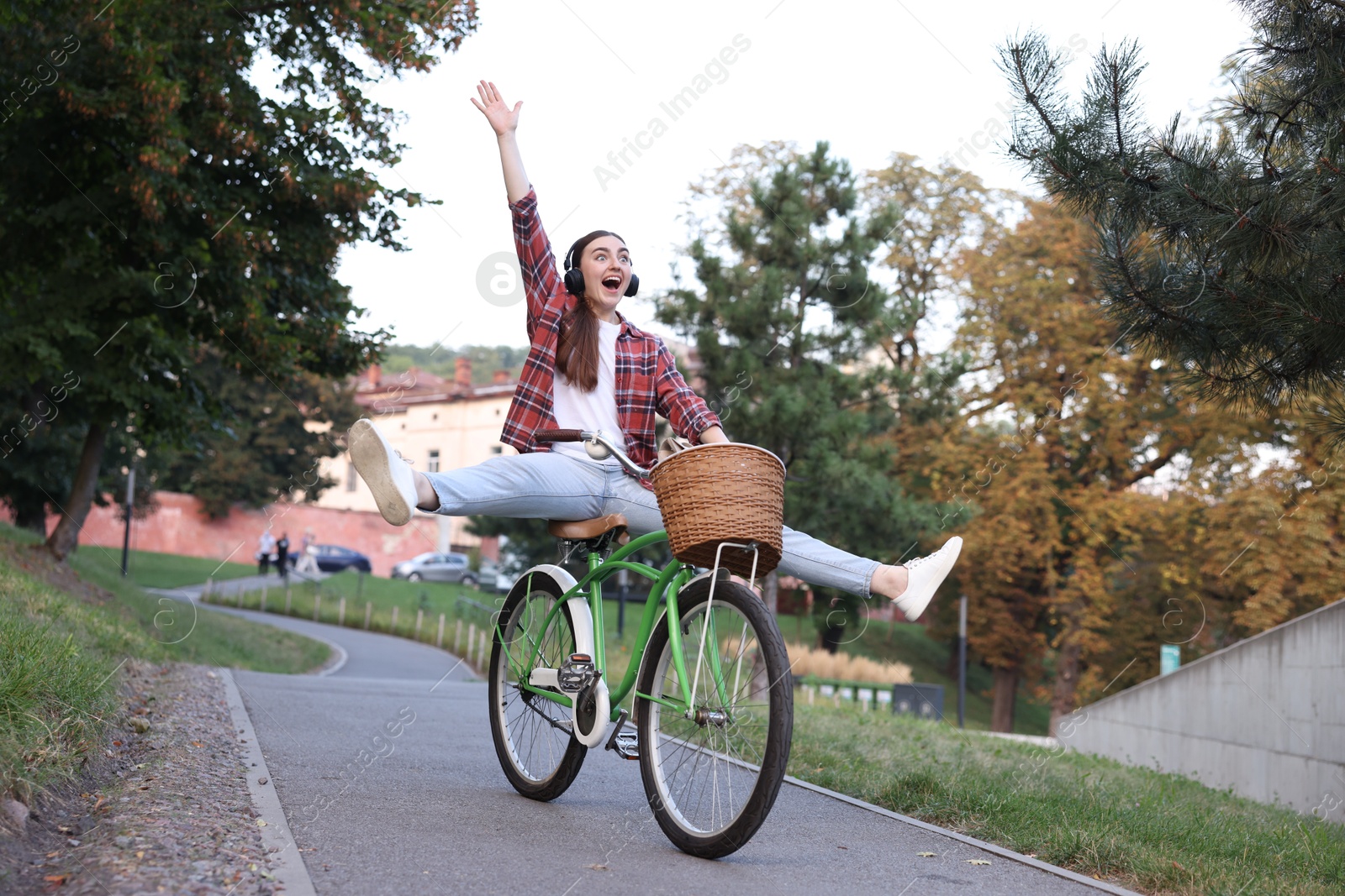Photo of Emotional woman with headphones riding bicycle in park
