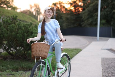 Photo of Happy woman riding bicycle on city street. Space for text