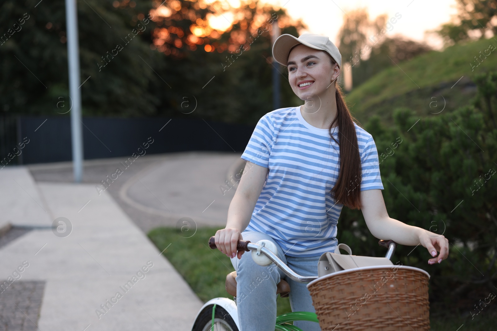 Photo of Happy woman riding bicycle on city street. Space for text