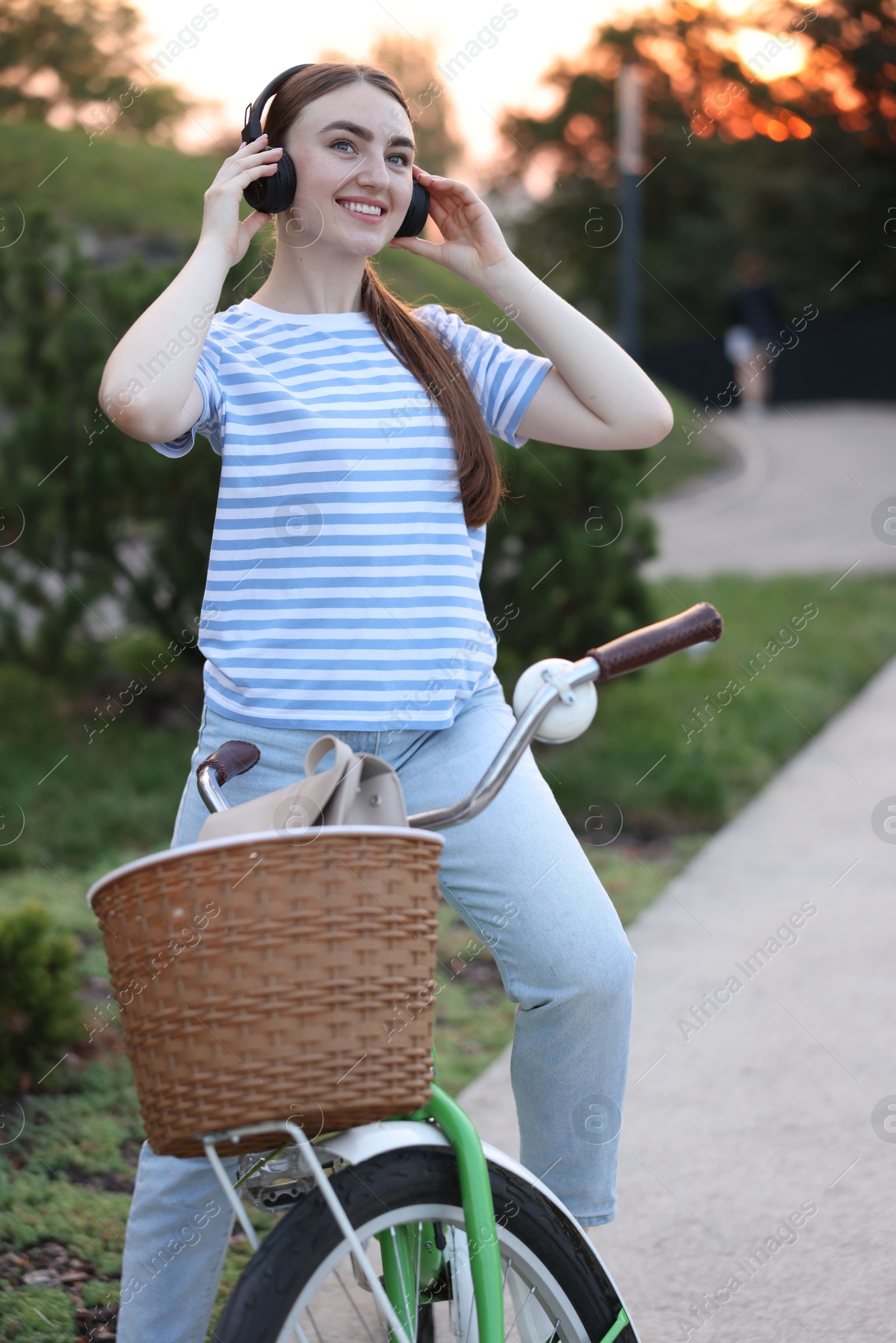 Photo of Beautiful woman listening to music while riding bicycle in park