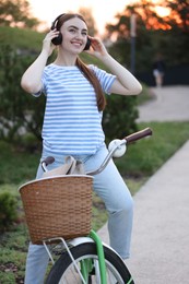 Photo of Beautiful woman listening to music while riding bicycle in park