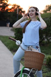 Photo of Beautiful woman listening to music while riding bicycle in park