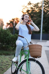 Photo of Beautiful woman listening to music while riding bicycle in park