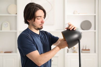 Photo of Man changing light bulb in lamp at home