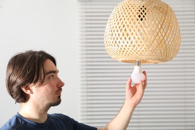 Photo of Man changing light bulb in lamp at home