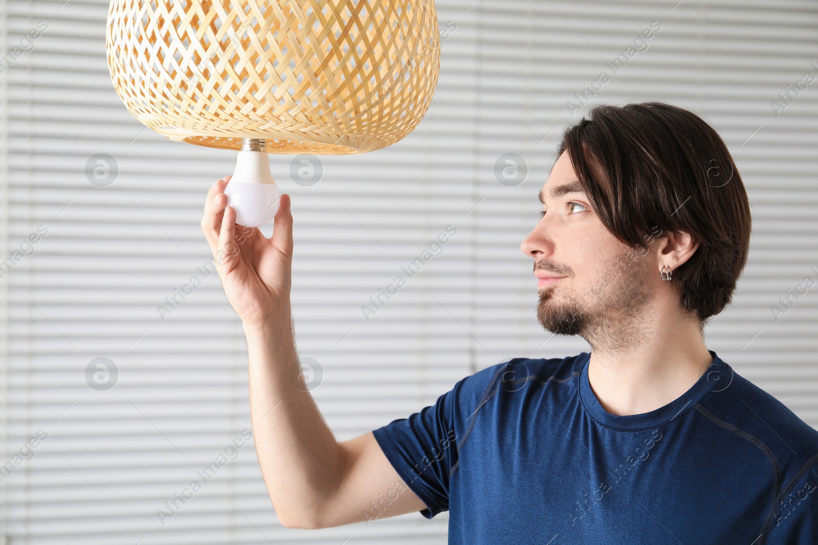 Photo of Man changing light bulb in lamp at home