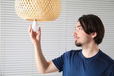 Photo of Man changing light bulb in lamp at home