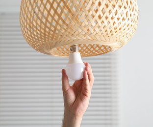 Photo of Man changing light bulb in lamp at home, closeup