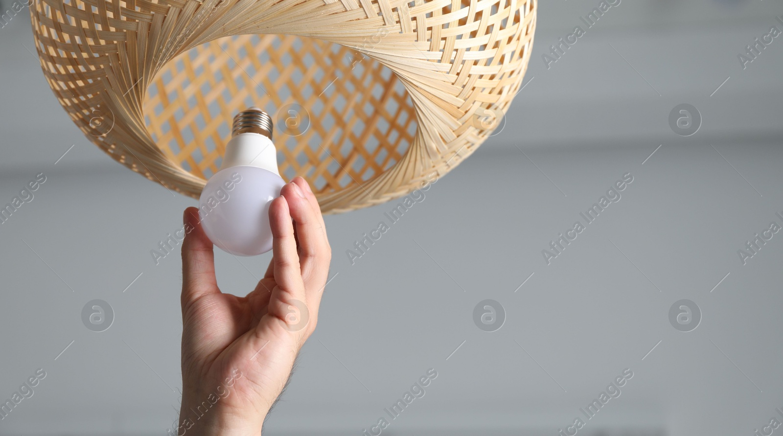 Photo of Man changing light bulb in lamp at home, closeup. Space for text
