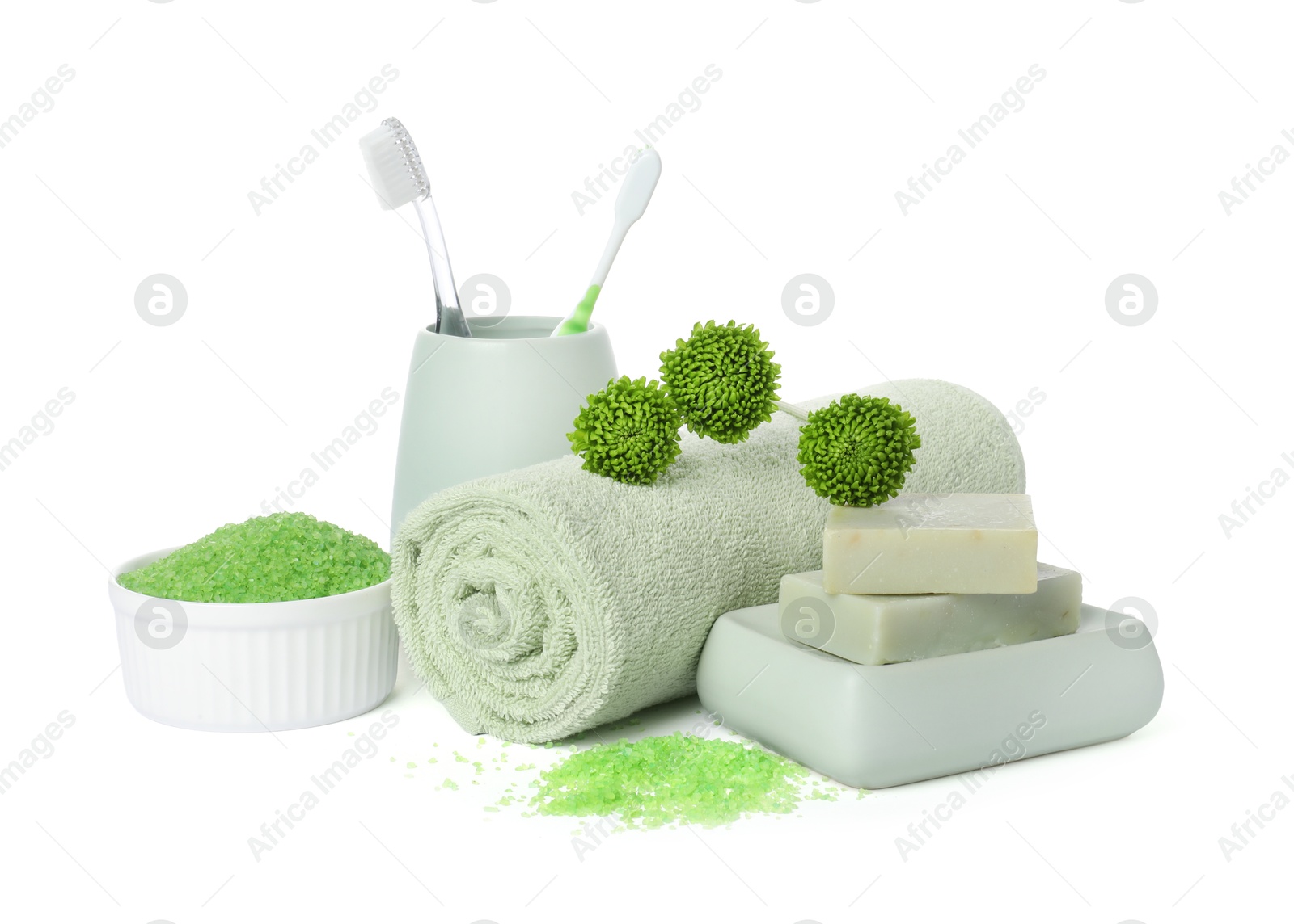 Photo of Rolled fresh terry towel, cosmetic products, toothbrushes and green flowers isolated on white