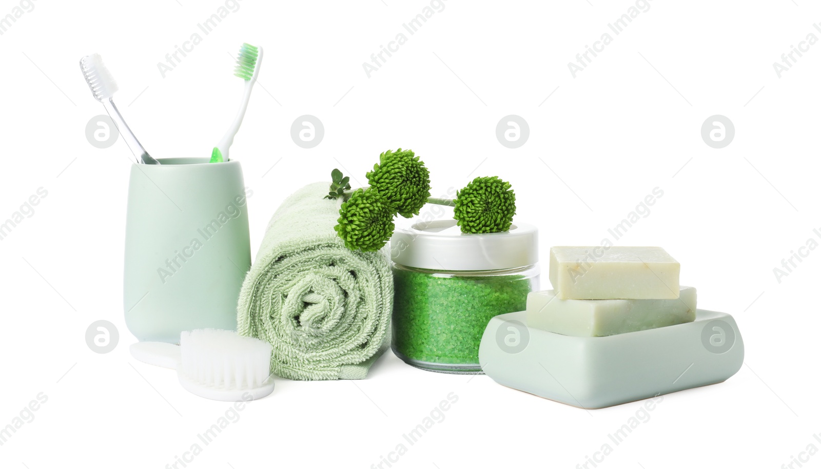 Photo of Rolled fresh terry towel, cosmetic products, toothbrushes and green flowers isolated on white