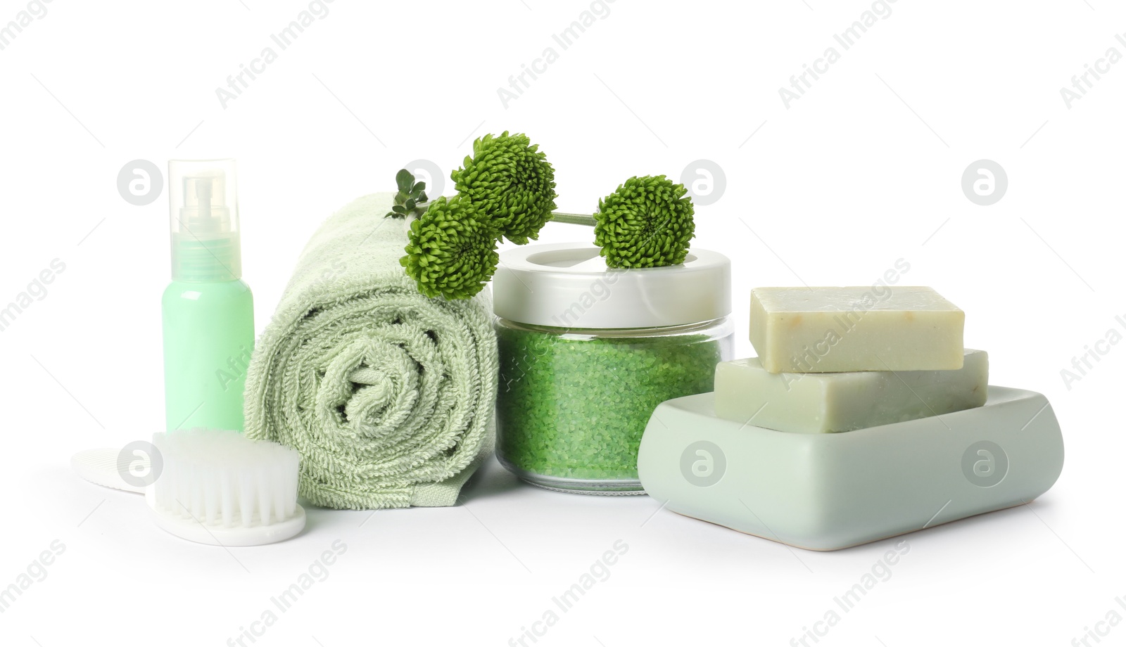 Photo of Rolled fresh terry towel, cosmetic products, brush and green flowers isolated on white