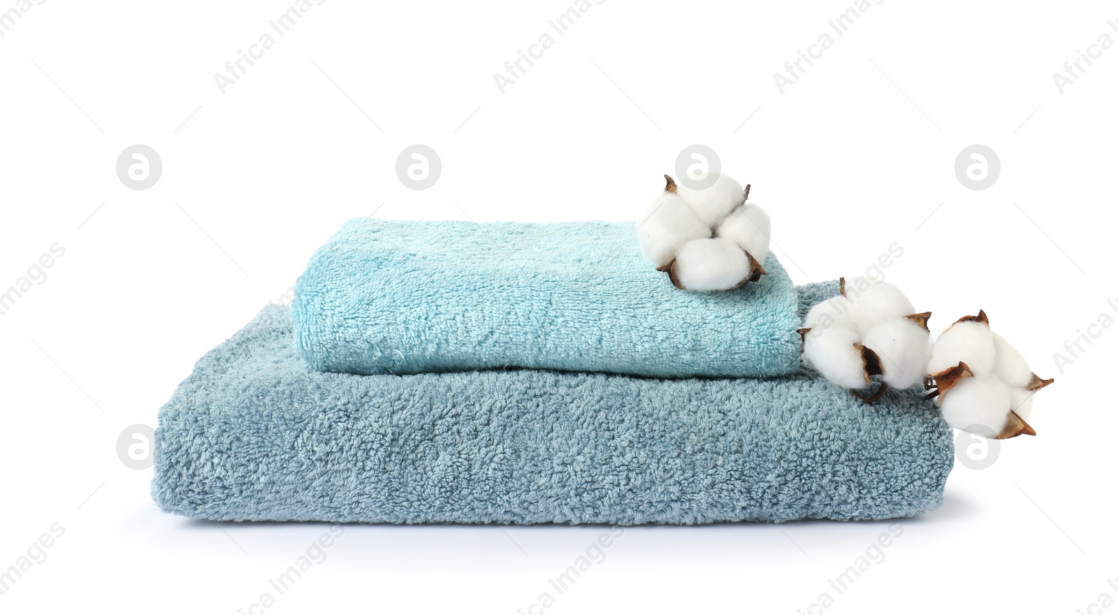 Photo of Stack of fresh terry towels and cotton flowers isolated on white