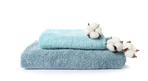 Photo of Stack of fresh terry towels and cotton flowers isolated on white