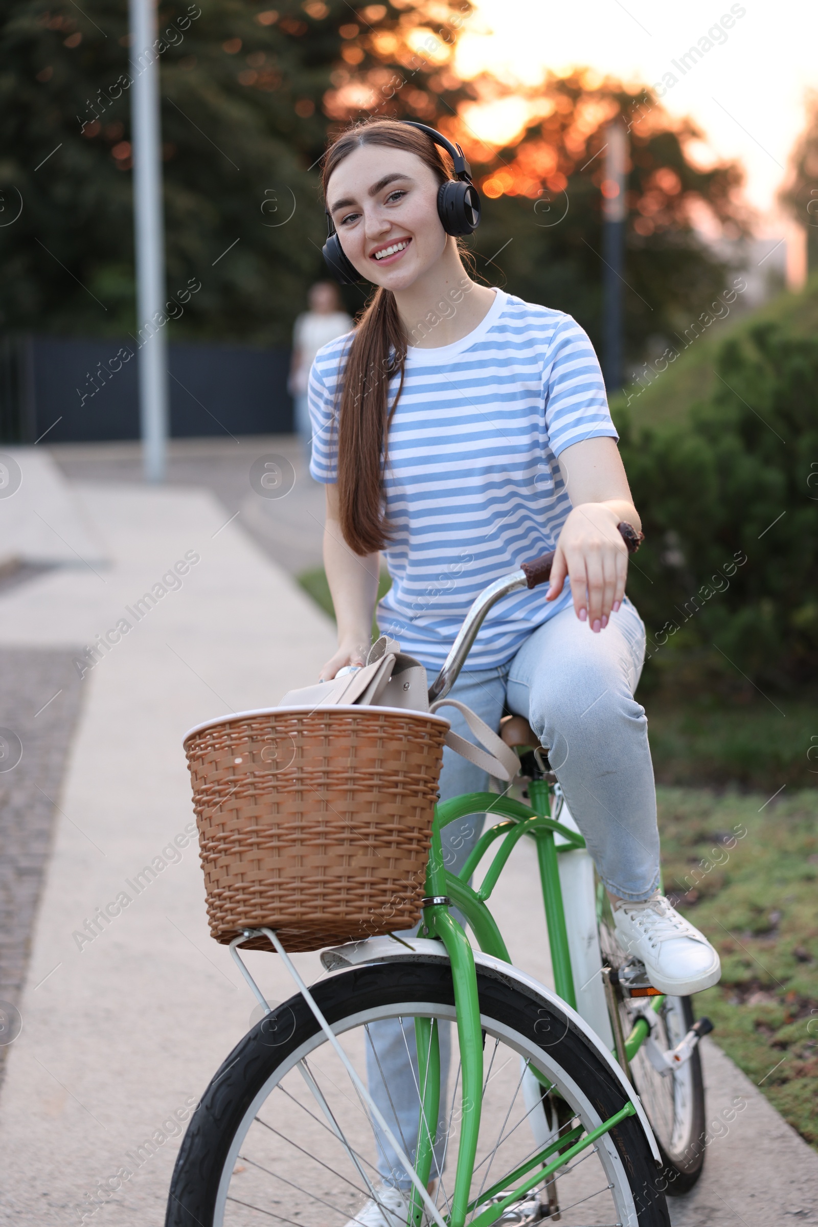 Photo of Beautiful woman listening to music while riding bicycle in park