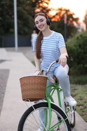 Photo of Beautiful woman listening to music while riding bicycle in park