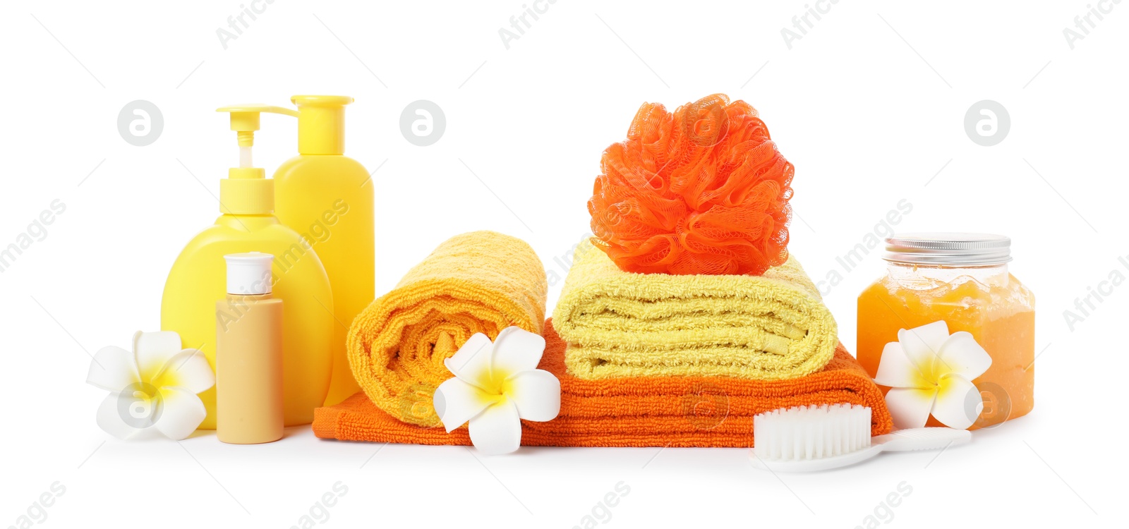Photo of Stack of fresh terry towels, cosmetic products, sponge, brush and plumeria flowers isolated on white