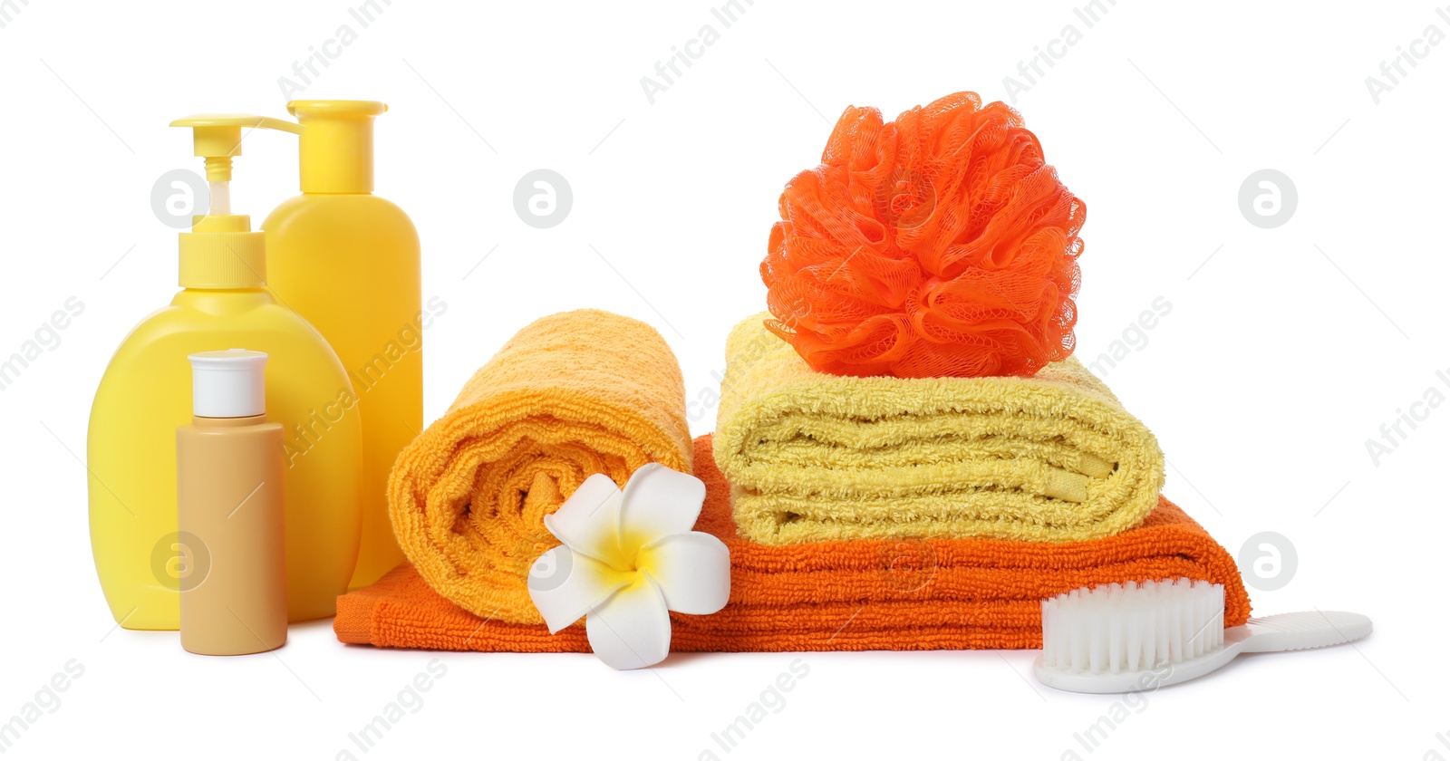 Photo of Stack of fresh terry towels, cosmetic products, sponge, brush and plumeria flower isolated on white