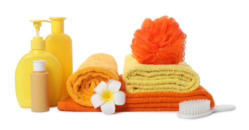 Photo of Stack of fresh terry towels, cosmetic products, sponge, brush and plumeria flower isolated on white