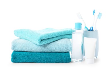 Photo of Stack of fresh terry towels, cosmetic products and toothbrushes isolated on white