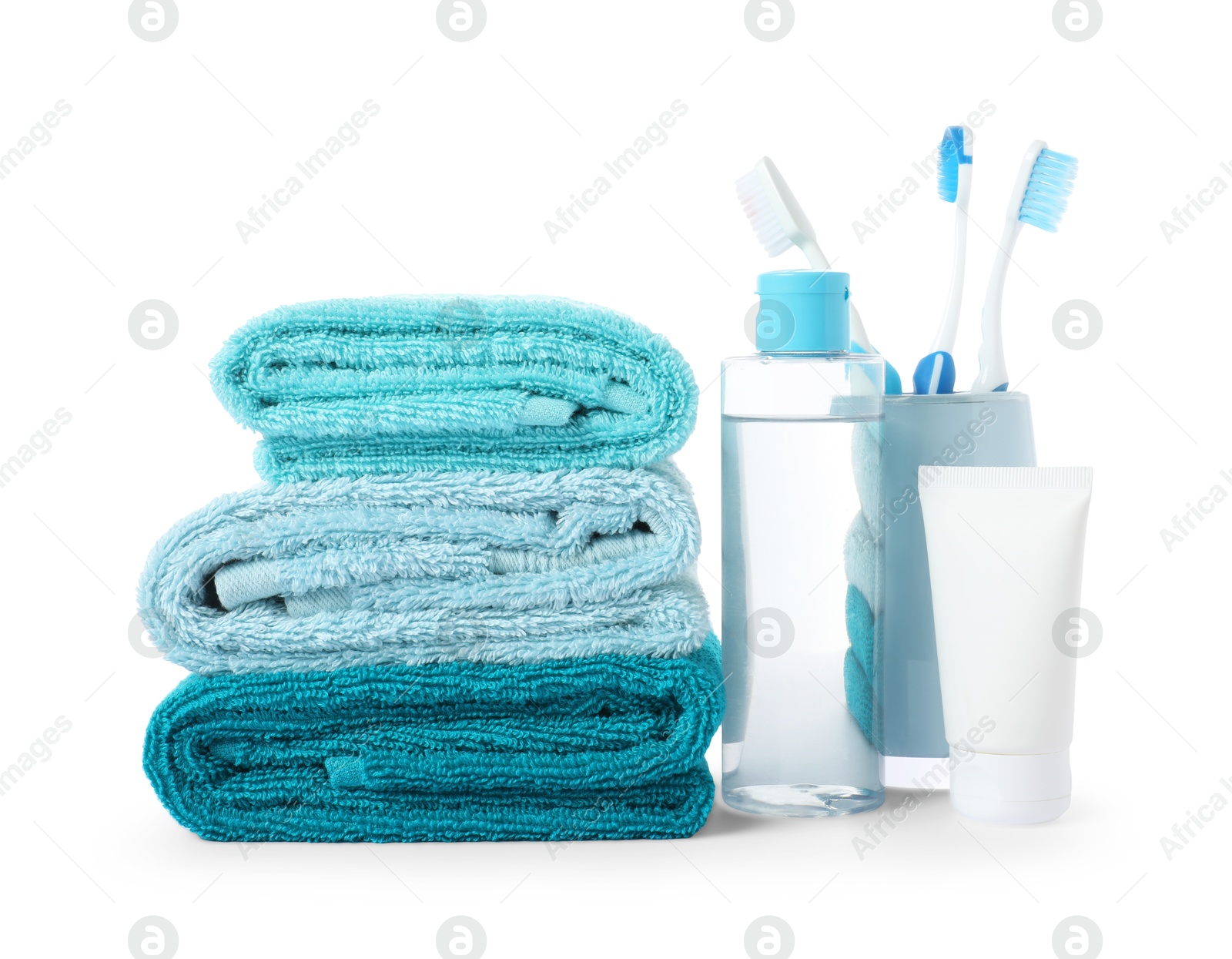 Photo of Stack of fresh terry towels, cosmetic products and toothbrushes isolated on white