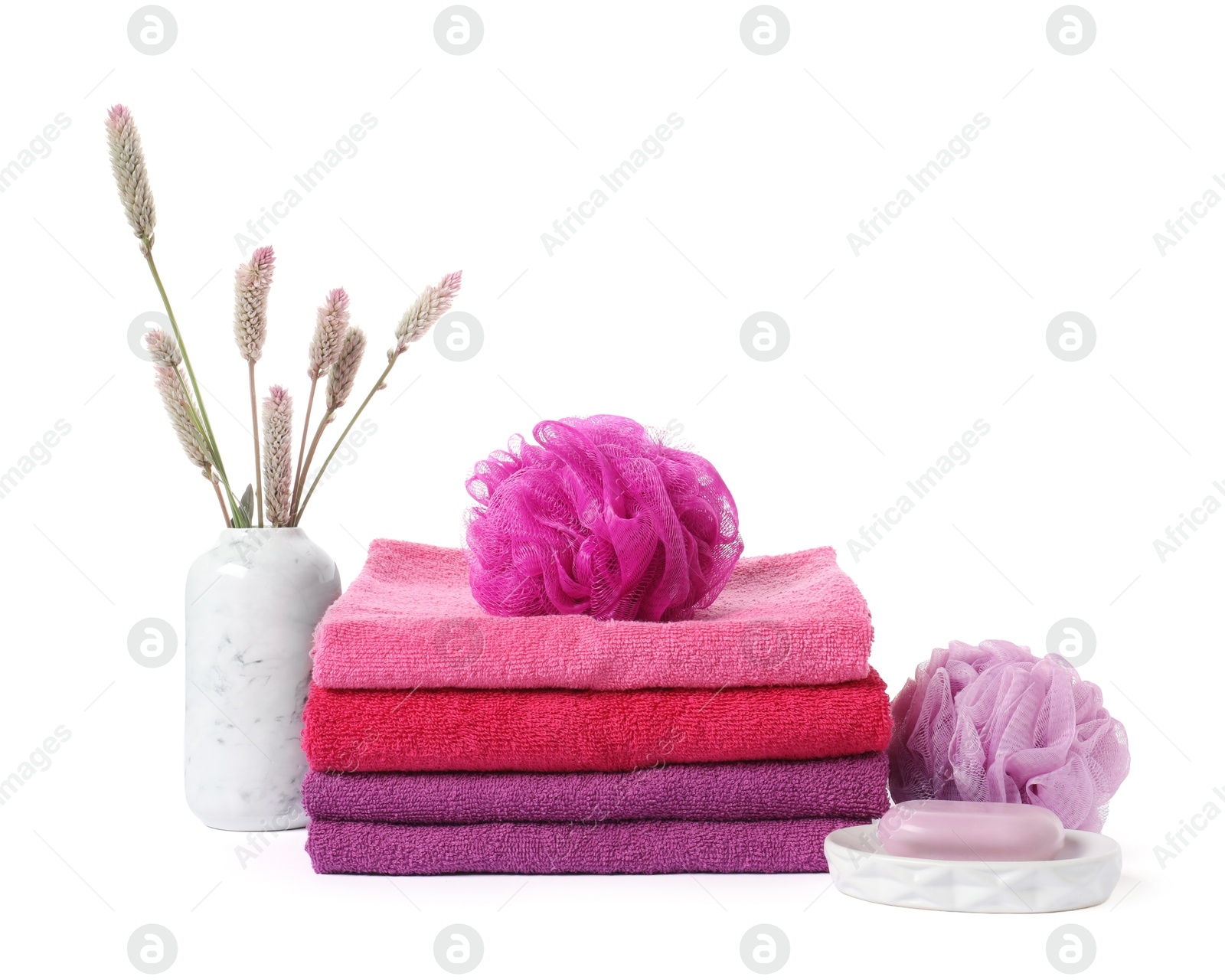 Photo of Stack of fresh terry towels, cosmetic products, sponges and floral decor isolated on white